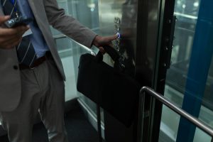 Mid section of Caucasian businessman using mobile phone in the elevator at office